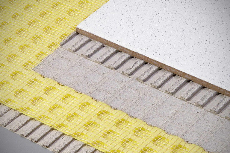 Structure d'une pose de carrelage au sol avec natte de découplage et colle à carrelage