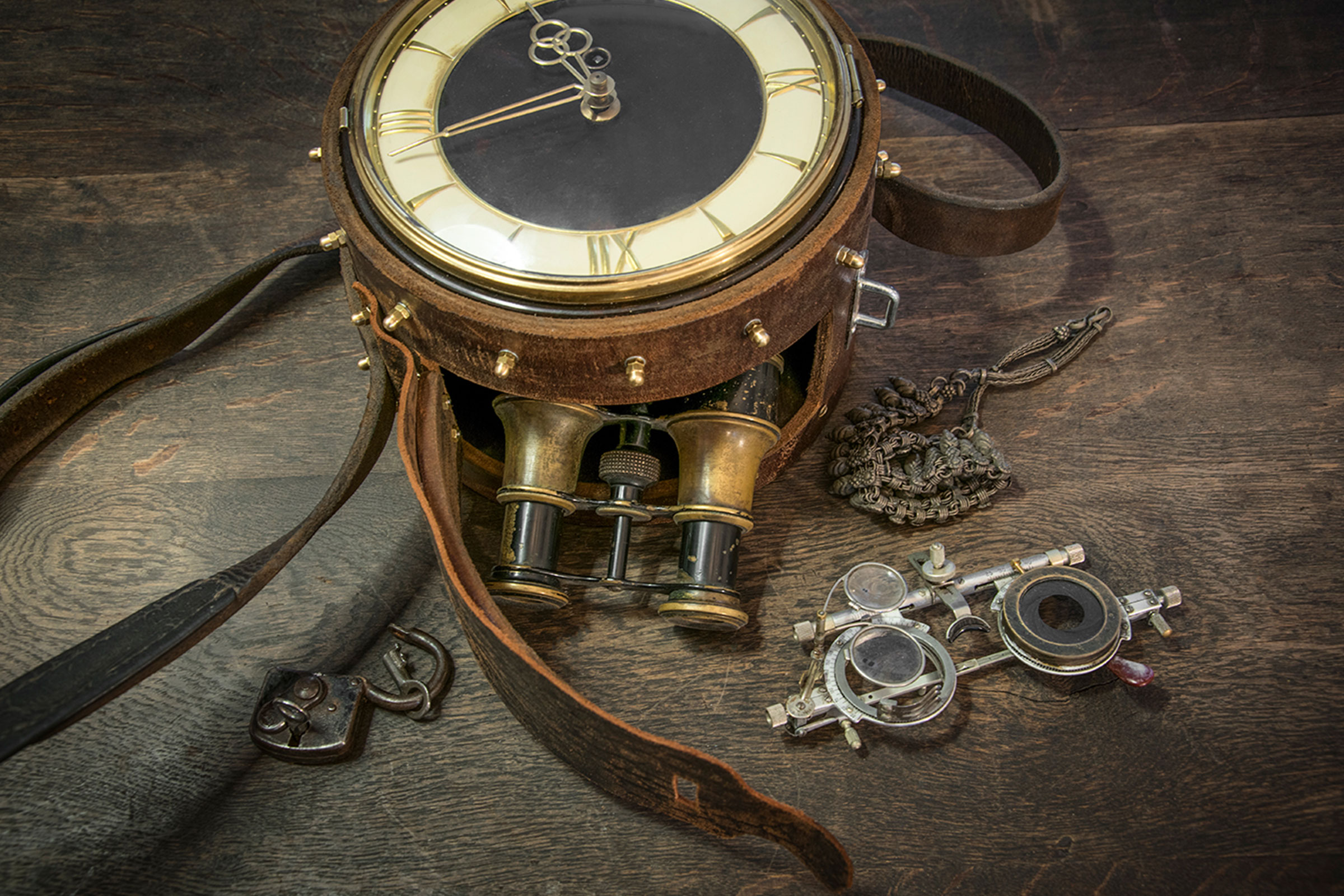 Scène vintage avec montre, jumelles, chaîne, cadenas et lunettes de mesure sur une surface en bois