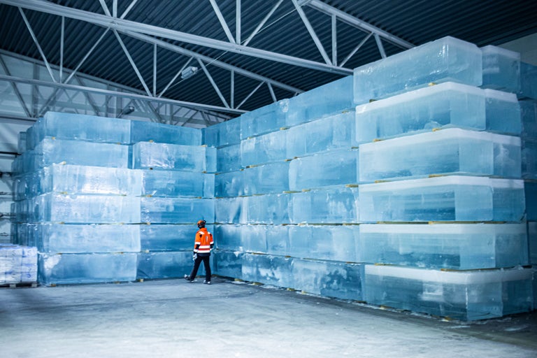 Grand entrepôt avec des blocs de glace empilés et une personne portant des vêtements de protection