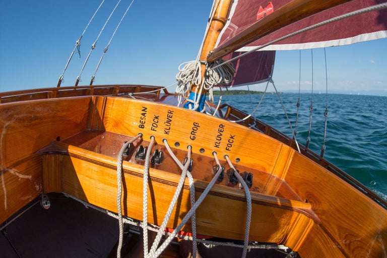 Detailansicht eines Holzbootes mit Segeln auf dem Wasser.