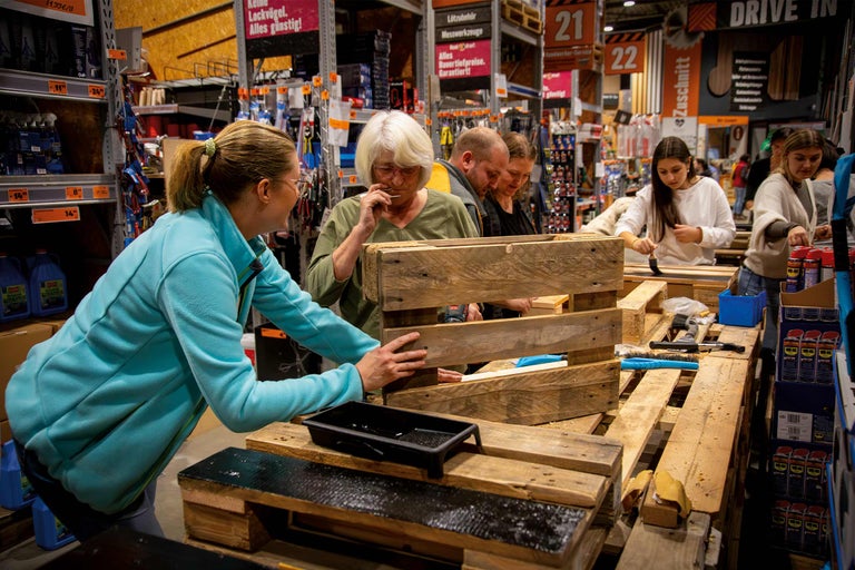 Des clients regardent et travaillent des palettes en bois au magasin Hornbach.