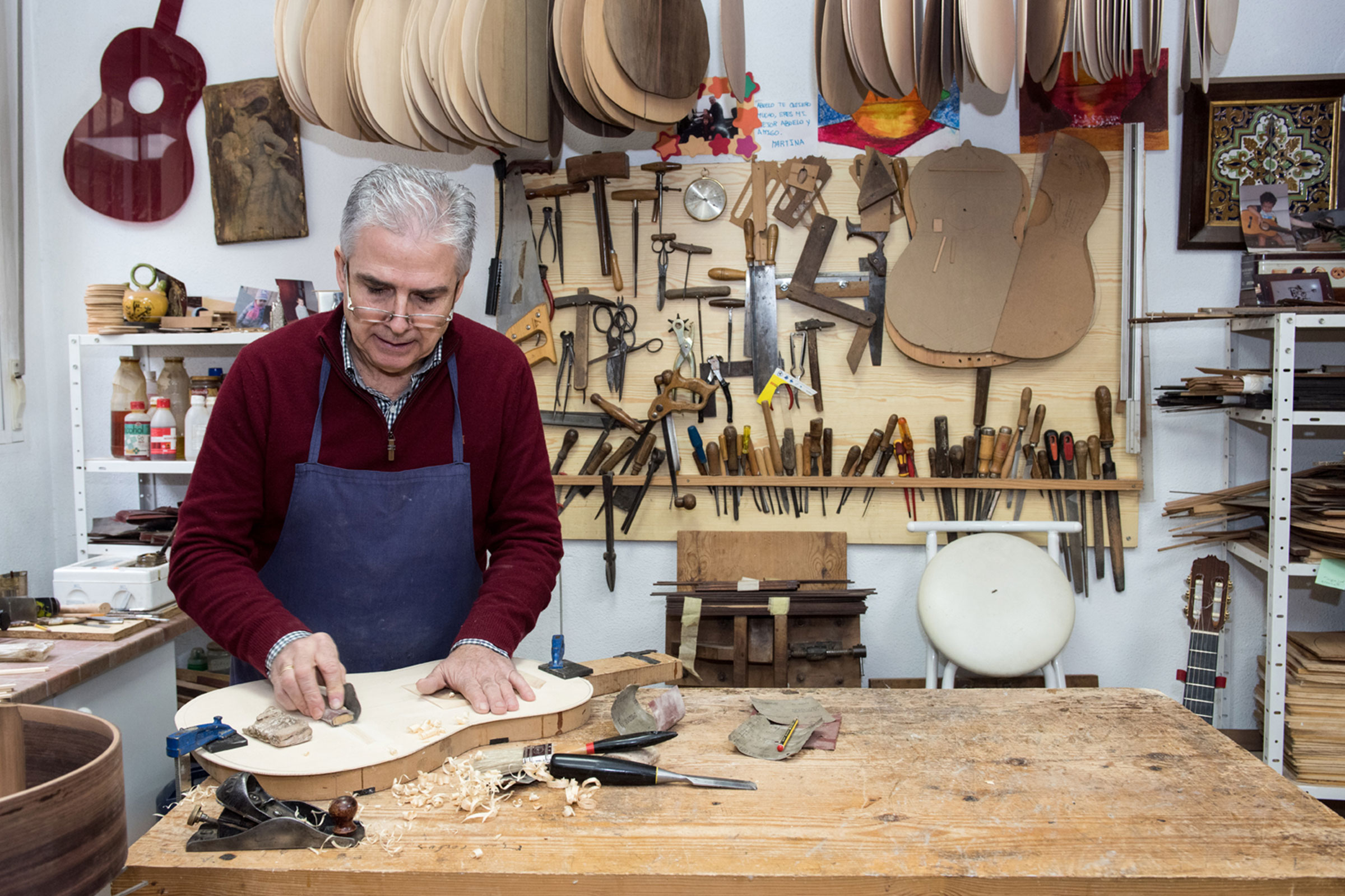 Un luthier travaille une guitare dans son atelier.