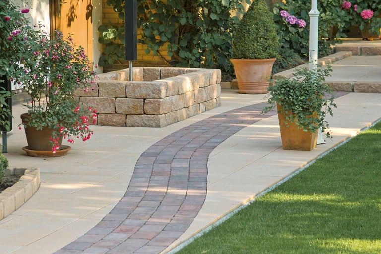 Chemin de jardin avec pavés, mur et plantes en pot