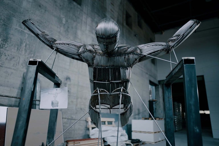 Sculpture d'un homme faite de barres de métal dans un entrepôt