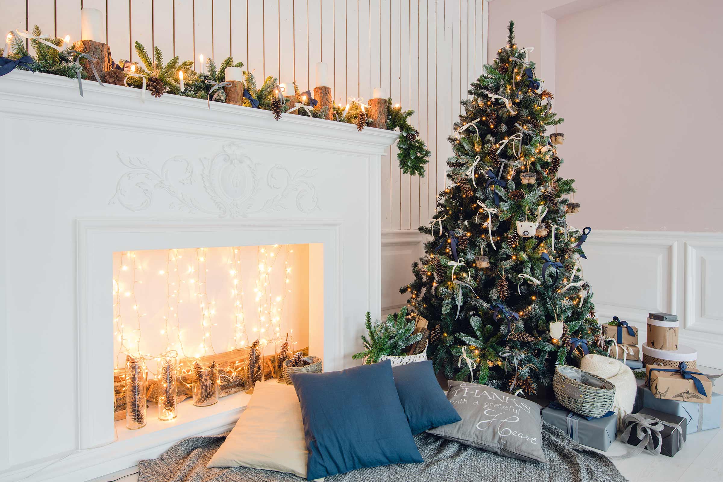 Dekorierter Weihnachtsbaum neben Kamin mit Dekoration und Geschenken