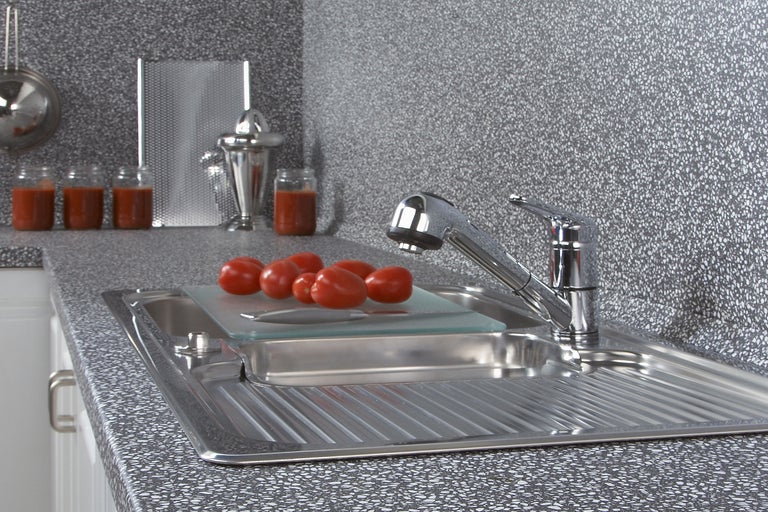 Scène de cuisine avec évier, robinet, planche à découper et tomates sur un plan de travail