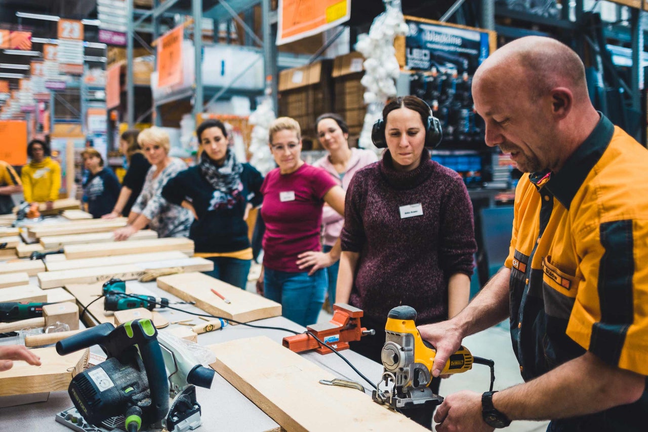 Eine Gruppe von Personen nimmt an einem Workshop mit Holzbearbeitungswerkzeugen von Dewalt teil.