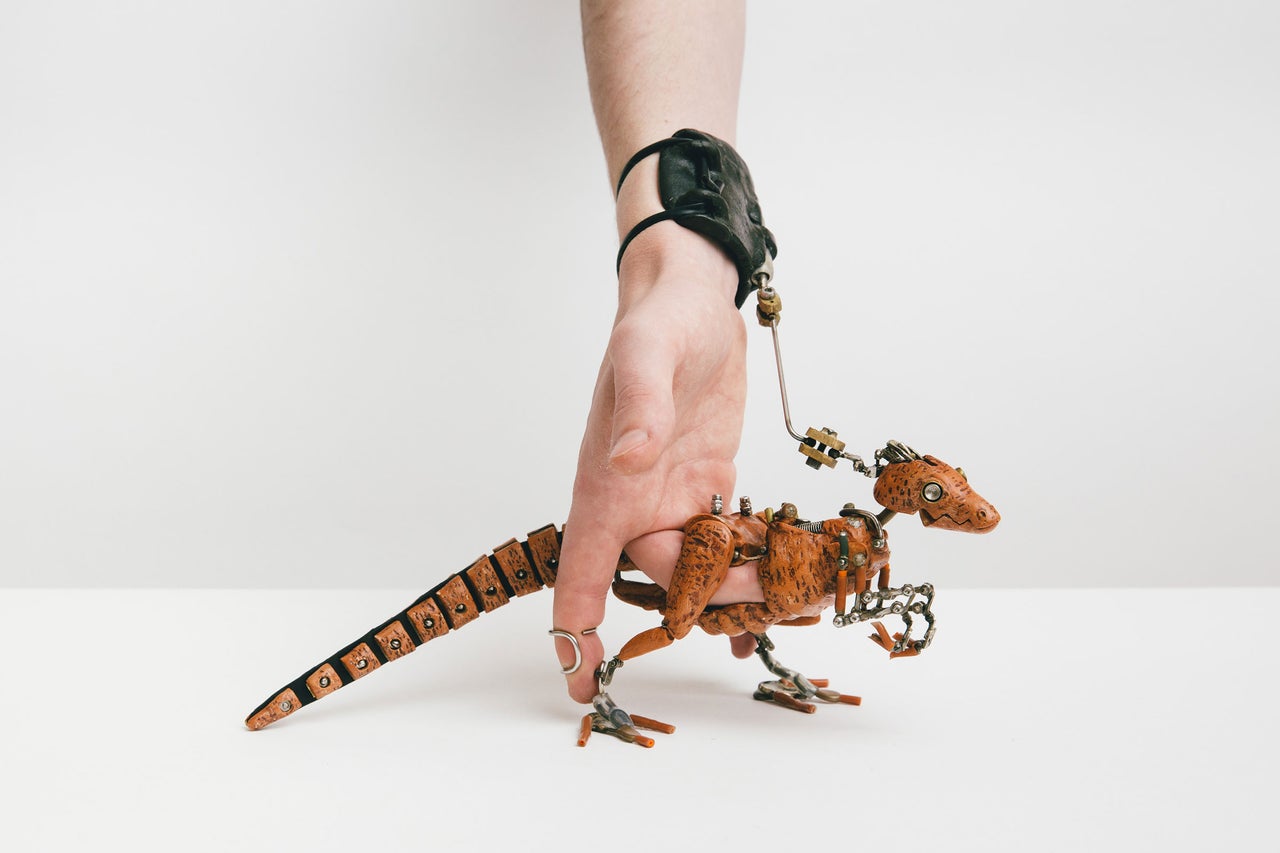 Une main tient une figurine de dinosaure robot en laisse