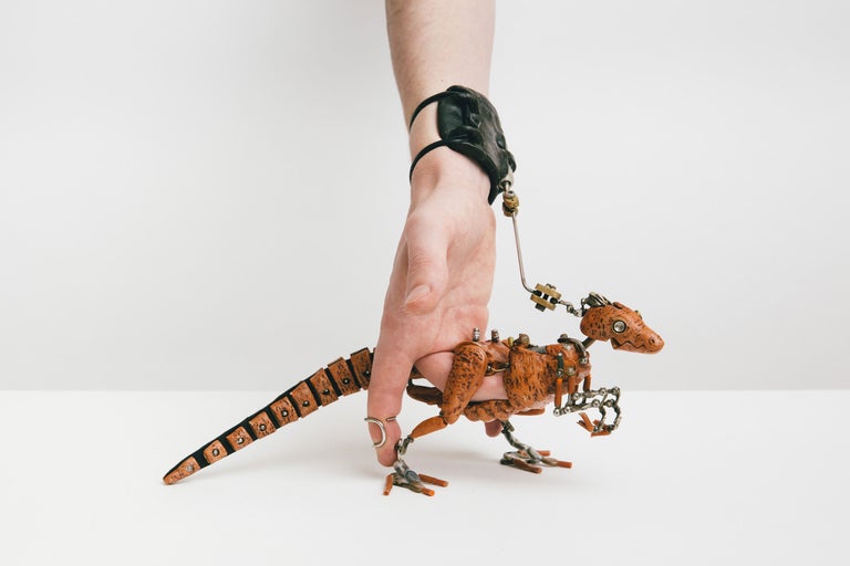 Hand hält eine Roboter-Dinosaurier-Figur an einer Leine