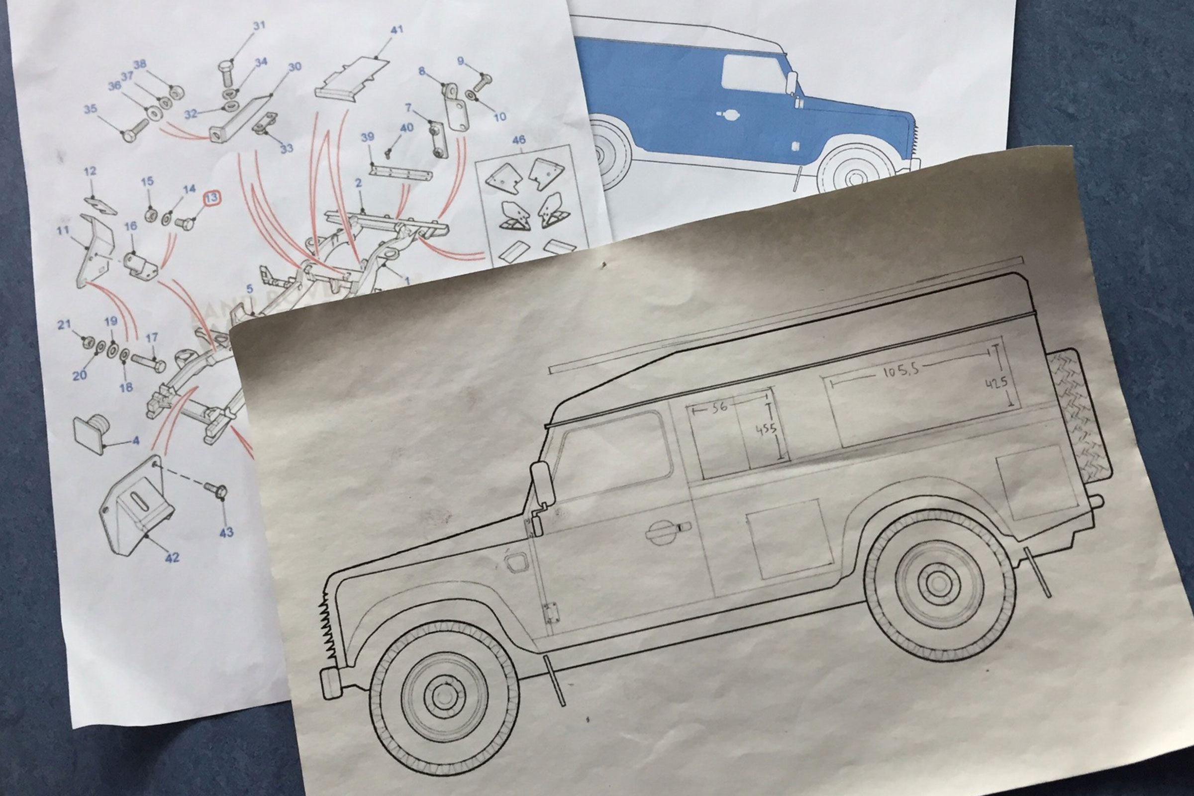 Mehrere Skizzen eines Land Rover Defender auf Papier.