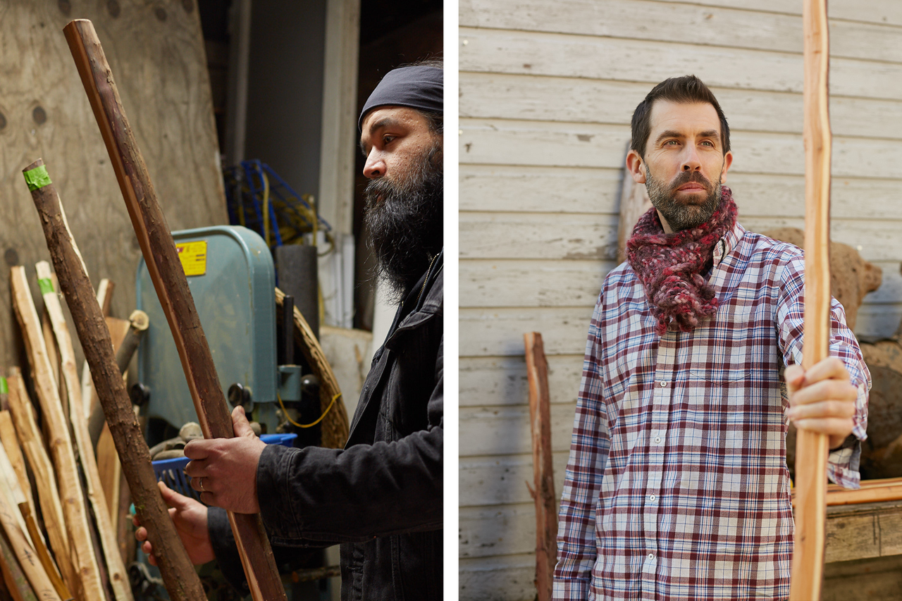 Deux hommes avec des bâtons en bois dans un atelier et à l'extérieur devant un mur en bois.