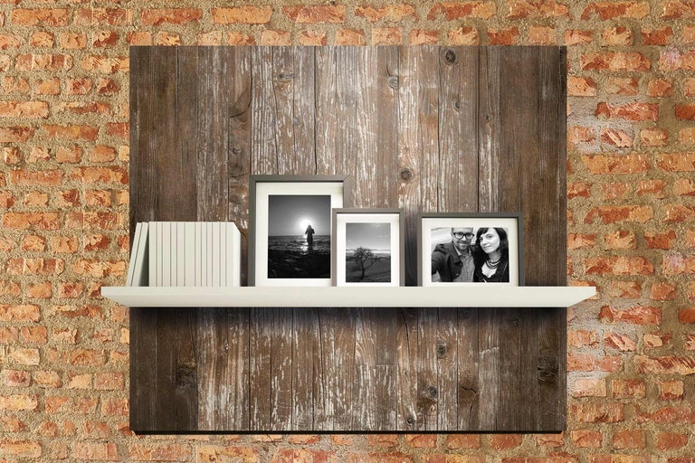Étagère murale avec des livres et des cadres photo devant un panneau de bois