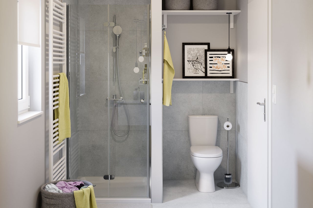 Salle de bain moderne et lumineuse avec douche en verre, murs carrelés gris, toilettes blanches et radiateur sèche-serviettes.
