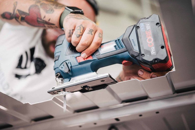 Scie sauteuse sans fil en cours d'utilisation pour scier une pièce.