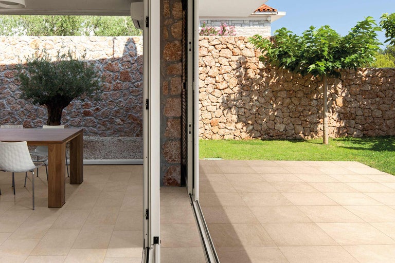 Espace extérieur avec mur de pierre, arbre et carreaux de sol.