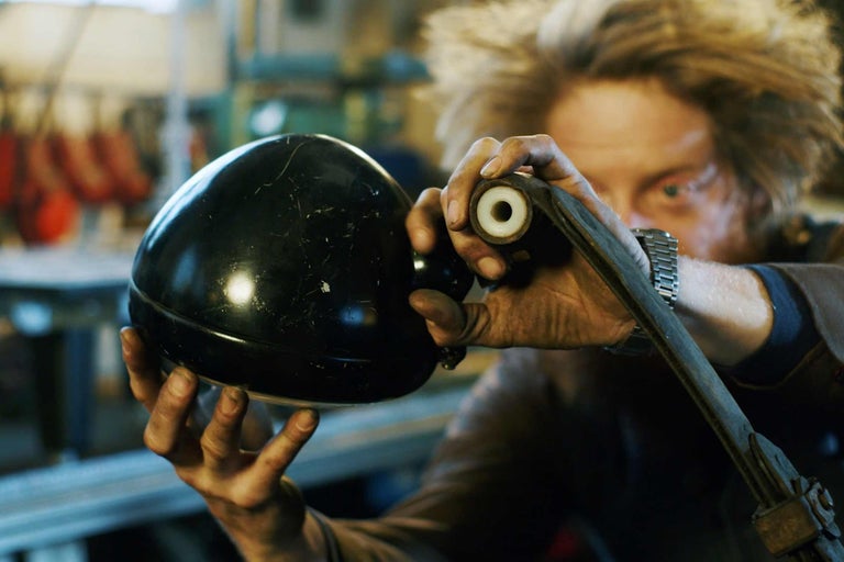 Une personne tient une lampe noire et une pièce métallique.