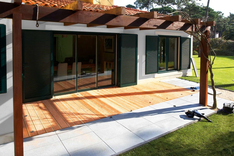 Maison avec terrasse en bois et dalles de pierre dans le jardin