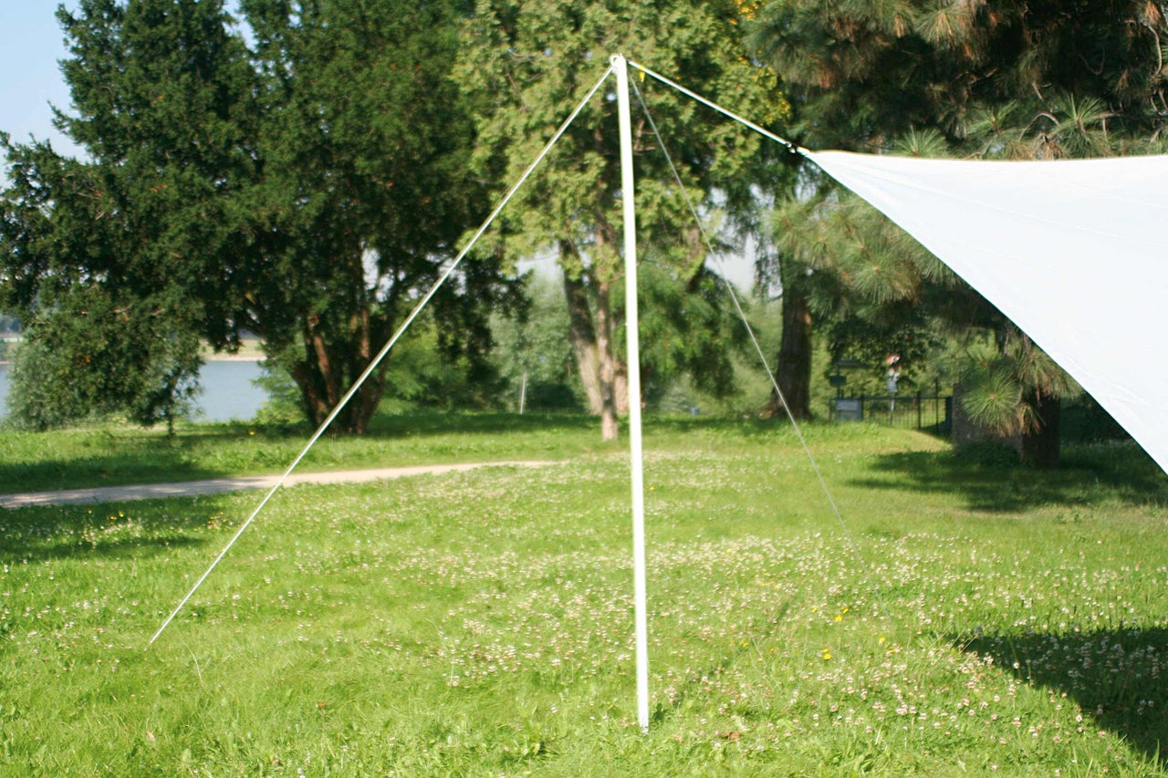 Weisses Sonnensegel auf einer Wiese, befestigt mit Seilen und einer Stange