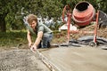 Un homme lisse le béton à la règle près d'une bétonnière Un homme lisse le béton à la règle près d'une bétonnière