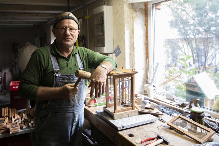 Handwerker mit Holzhammer in Werkstatt mit Holzbauteilen