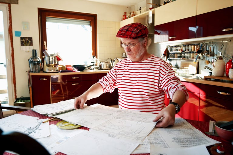 Un homme dans la cuisine regarde des plans sur la table.