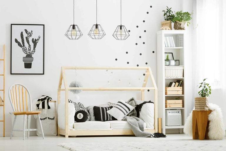 Chambre d'enfant lumineuse avec cadre de lit en bois, coussins, décoration et bibliothèque
