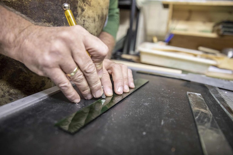 Ein Mann schneidet mit einem Glasschneider Glas auf einer Arbeitsfläche