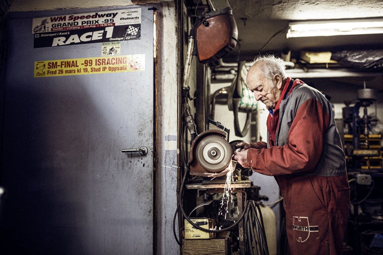 Un homme travaille avec une meuleuse dans un atelier. Une porte avec des autocollants et un casque de soudure sont visibles en arrière-plan. Le logo Würth est visible sur ses vêtements de travail.