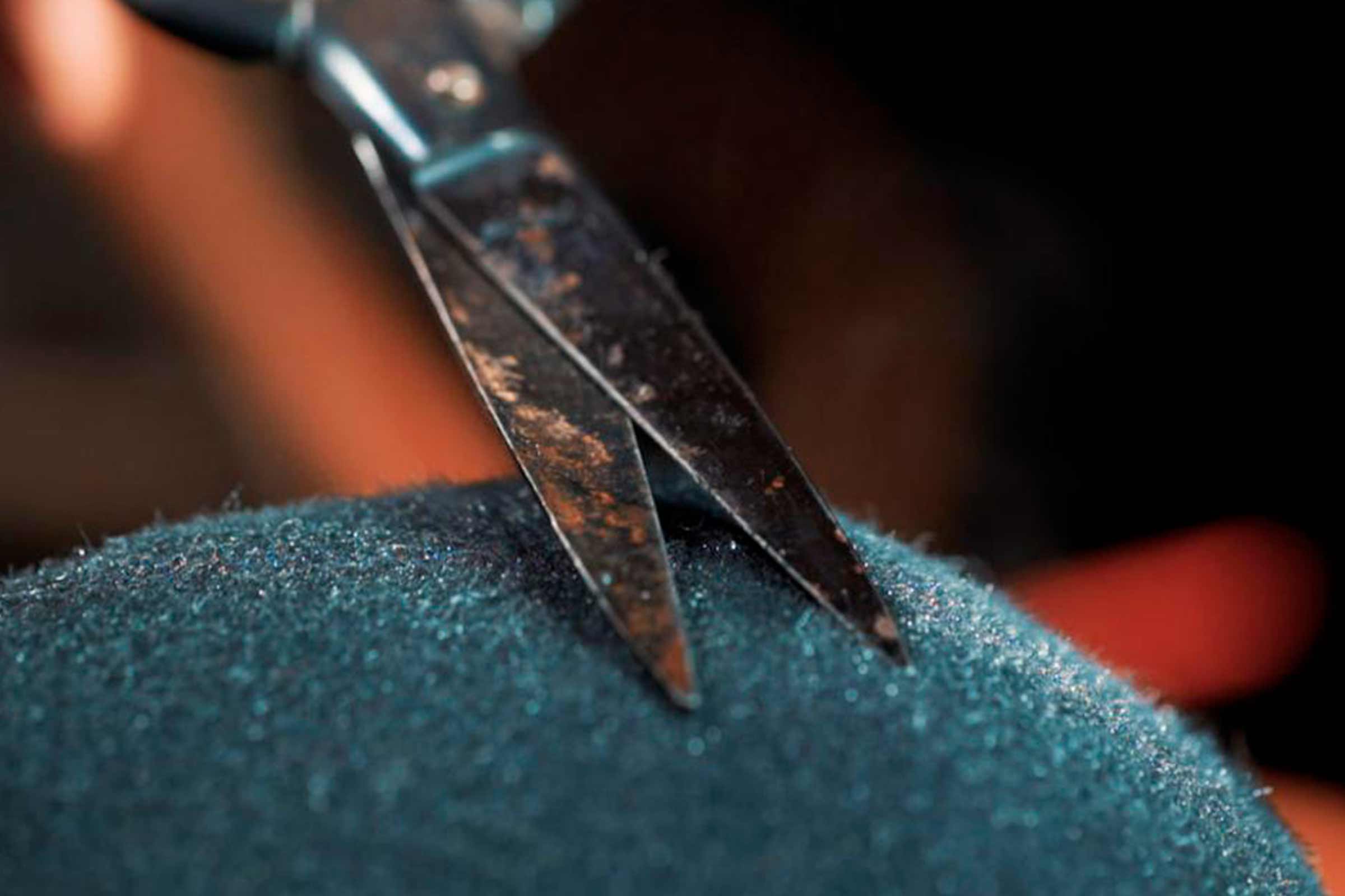 Une paire de ciseaux coupe un tissu bleu.