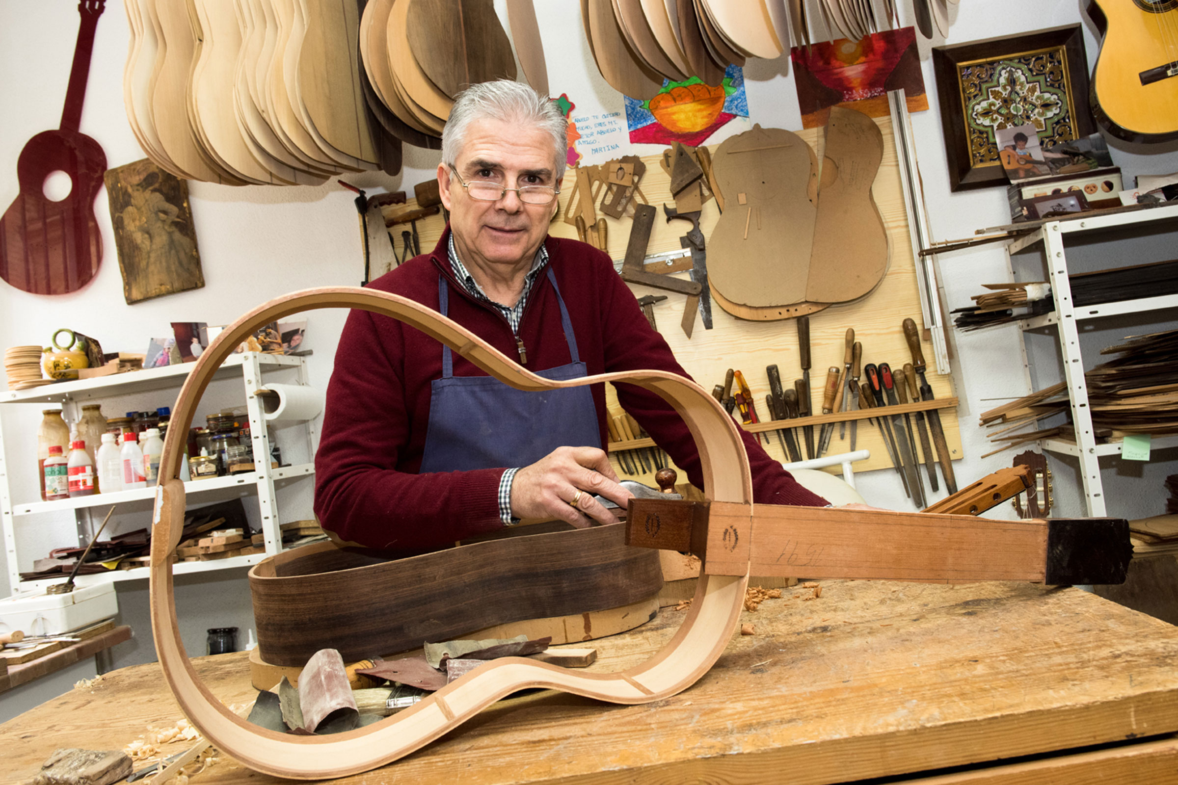 Luthier travaillant sur une guitare dans son atelier.