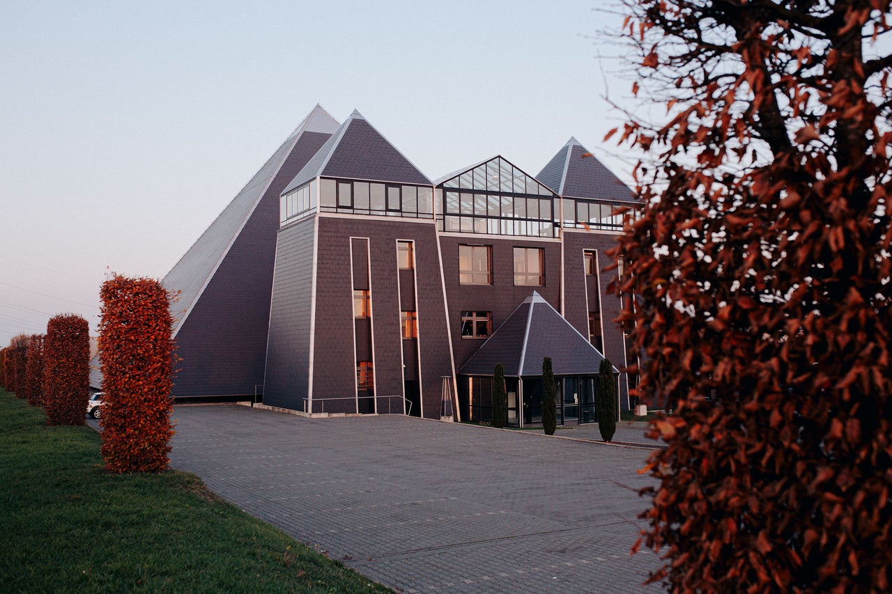 Aussenansicht eines Bürogebäudes mit pyramidenförmigen Dächern und angelegten Hecken