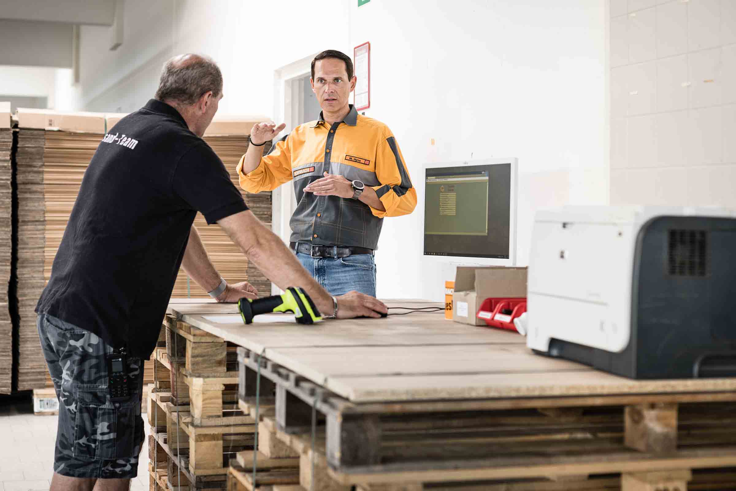 Deux employés travaillant avec un lecteur de codes-barres et un ordinateur sur une table en bois