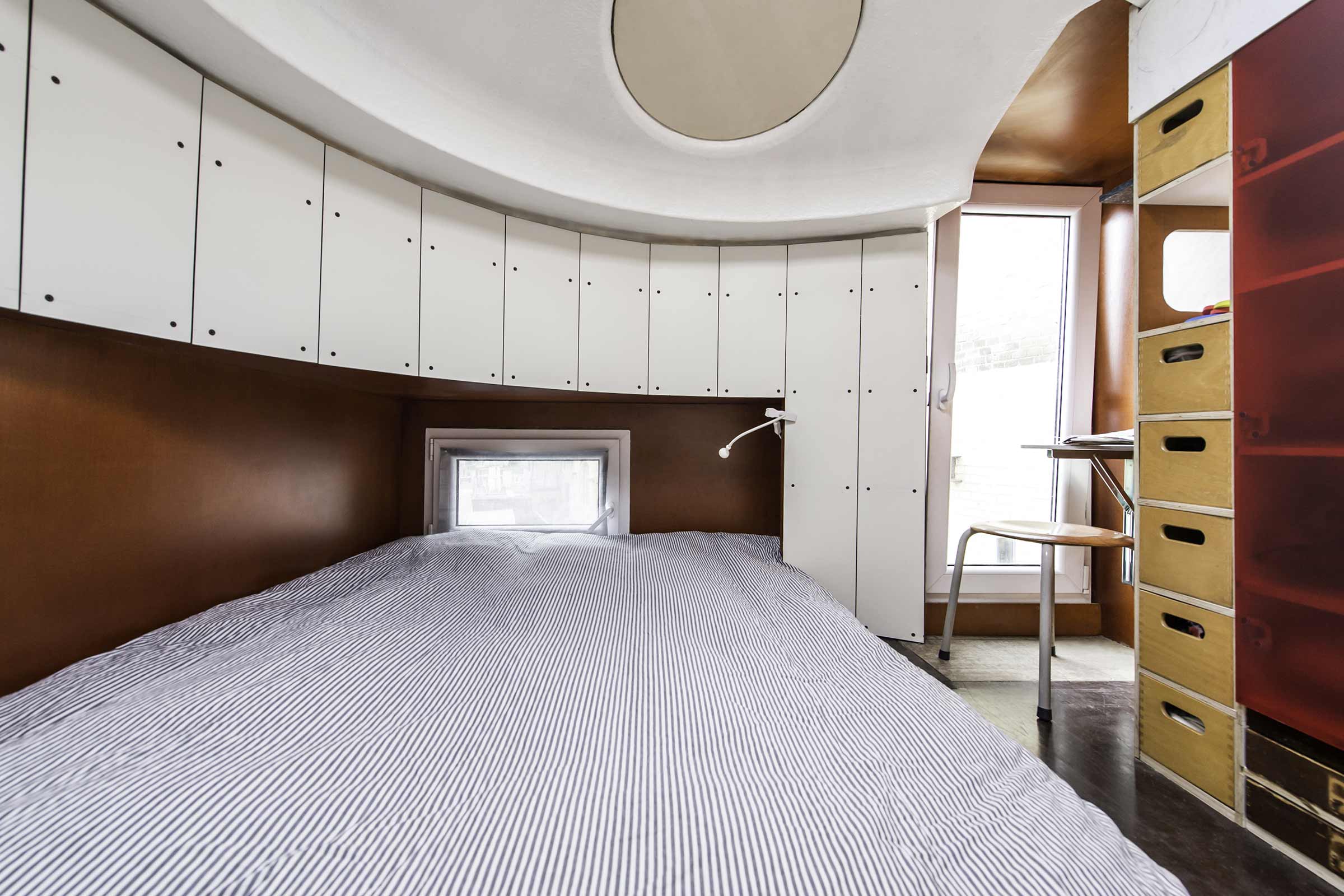 Schlafzimmer mit Bett, eingebauten weißen Schränken und Holzregalen