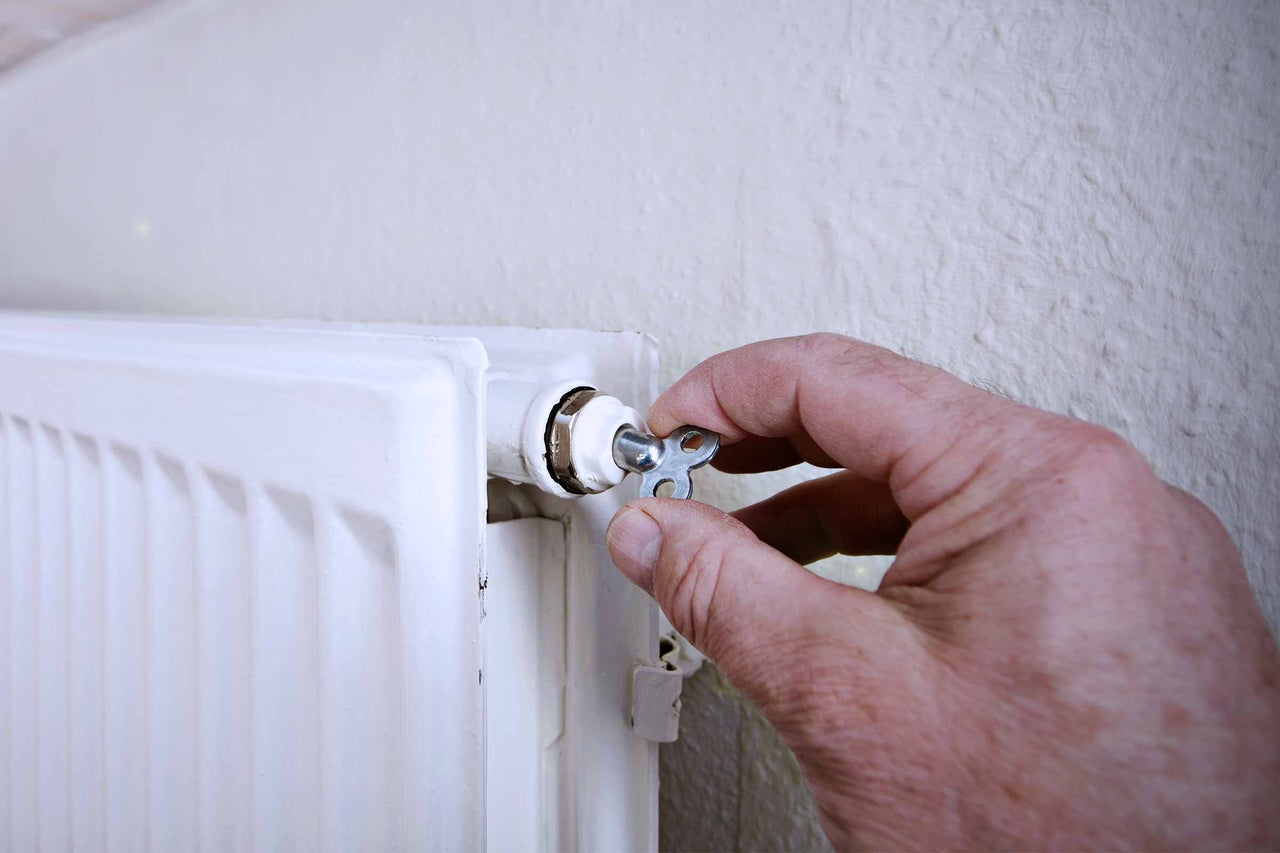 Main actionnant une clé de purge sur un radiateur