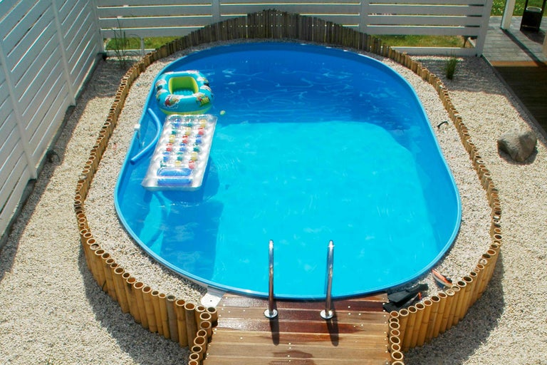Piscine gonflable avec échelle et bordure en bambou dans le jardin.