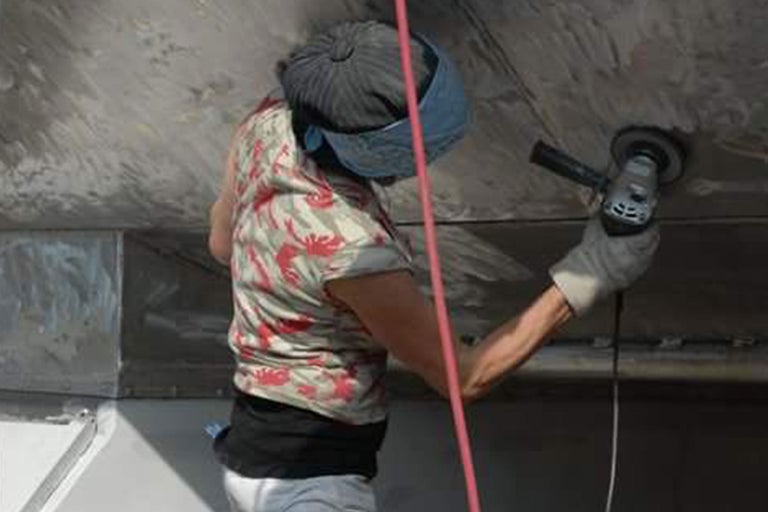 Une personne utilise une meuleuse pour travailler une surface.