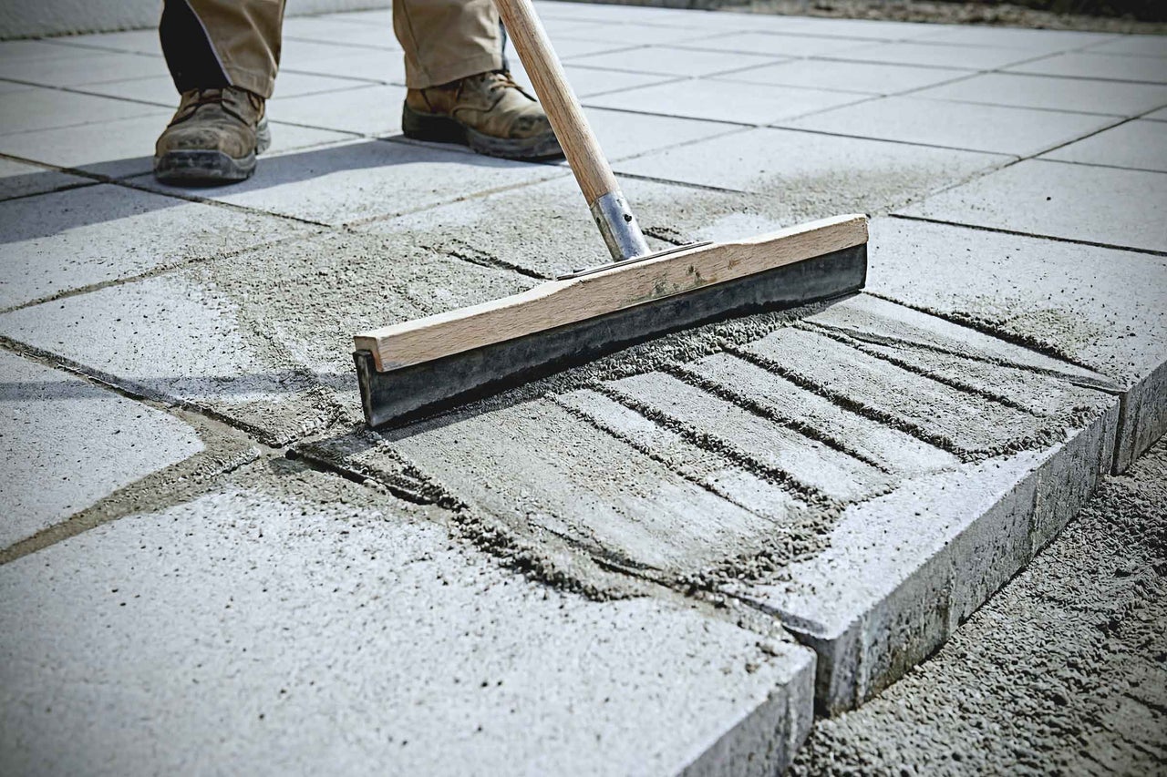 Produit de jointoiement balayé dans le pavage avec une raclette en caoutchouc