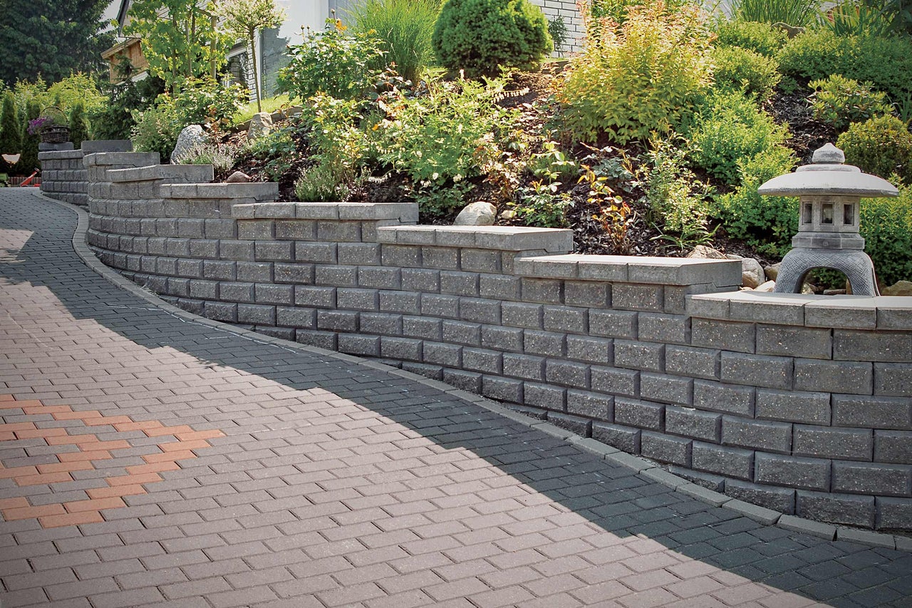 Gestaltungsidee für einen Garten mit Stützmauer und Pflasterweg.