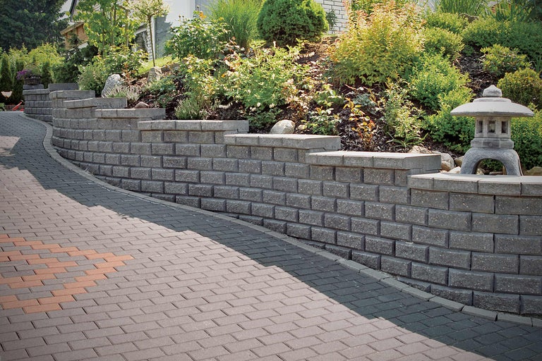 Gestaltungsidee für einen Garten mit Stützmauer und Pflasterweg.