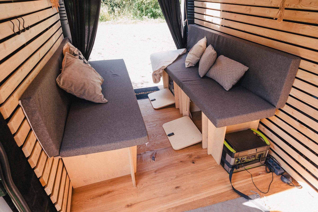 Intérieur d'une camionnette transformée avec coin salon et murs en bois