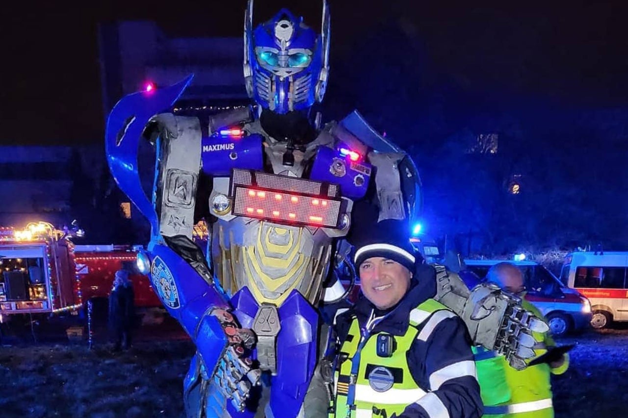 Personne en costume de Transformer avec des secouristes et des véhicules d'intervention en arrière-plan