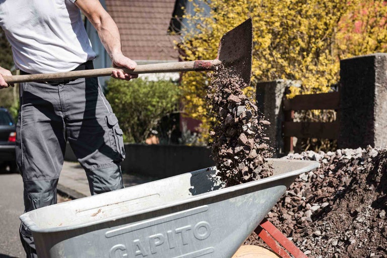 Un homme verse du gravier dans une brouette
