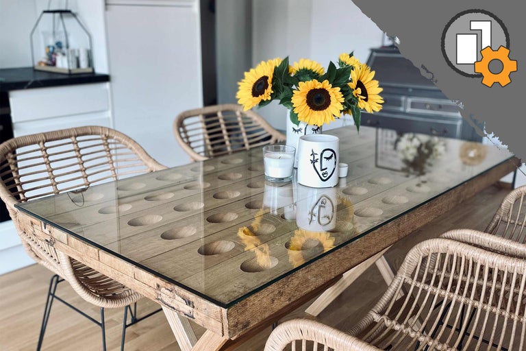 Table de salle à manger avec plateau en verre, éléments en bois et chaises en rotin