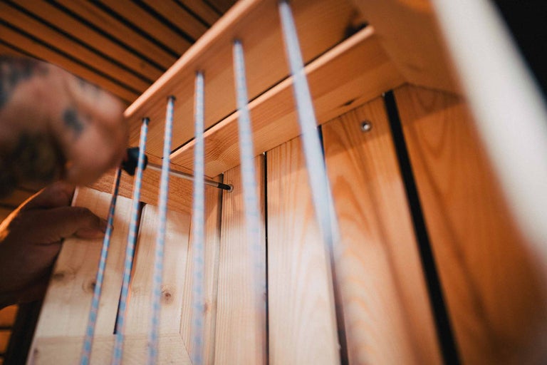 Gros plan d'une personne assemblant une étagère en bois avec un tournevis.