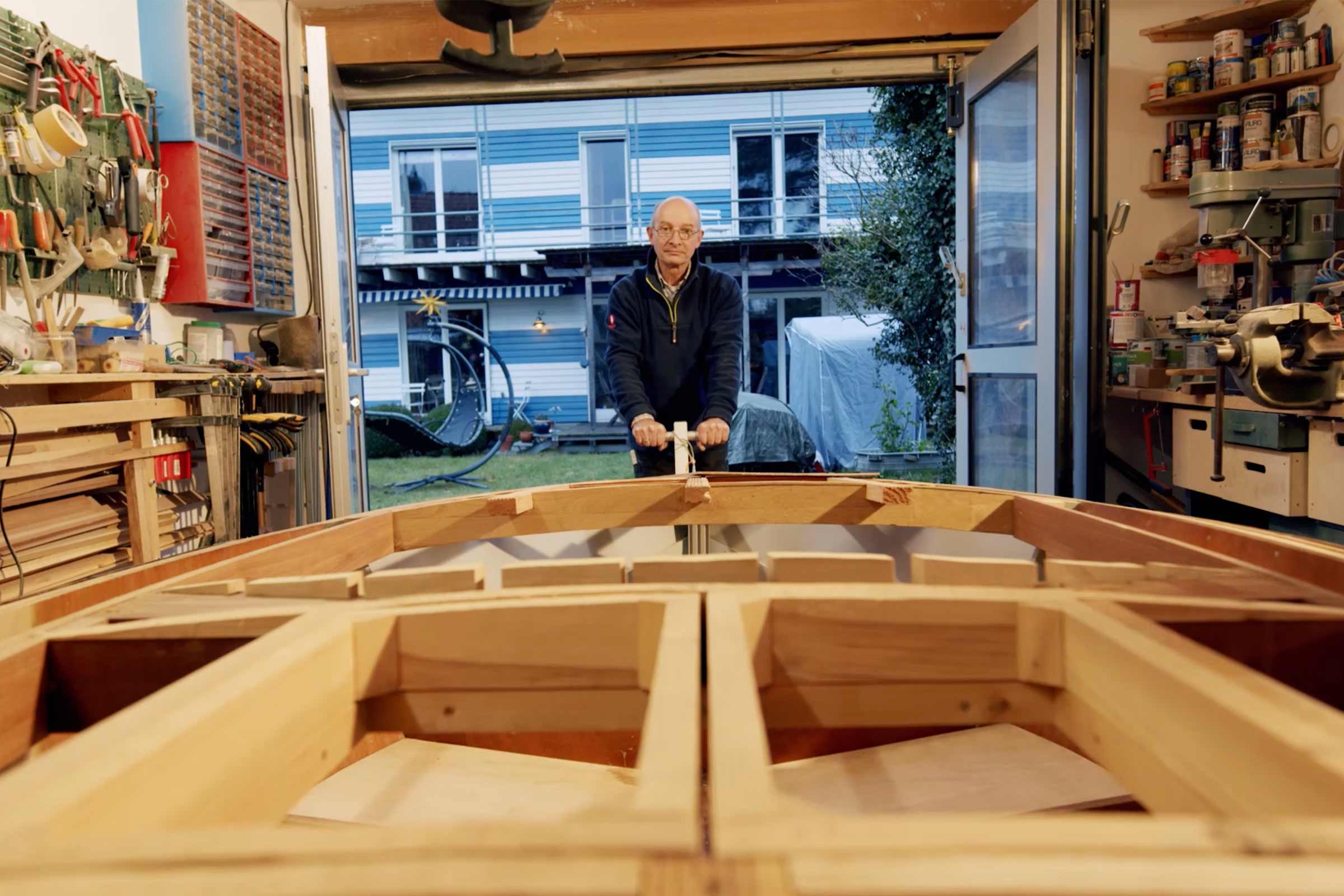 Un homme construit un bateau en bois dans un atelier.