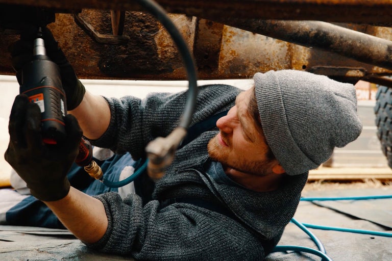Un homme utilise une clé à choc pour travailler sur une voiture