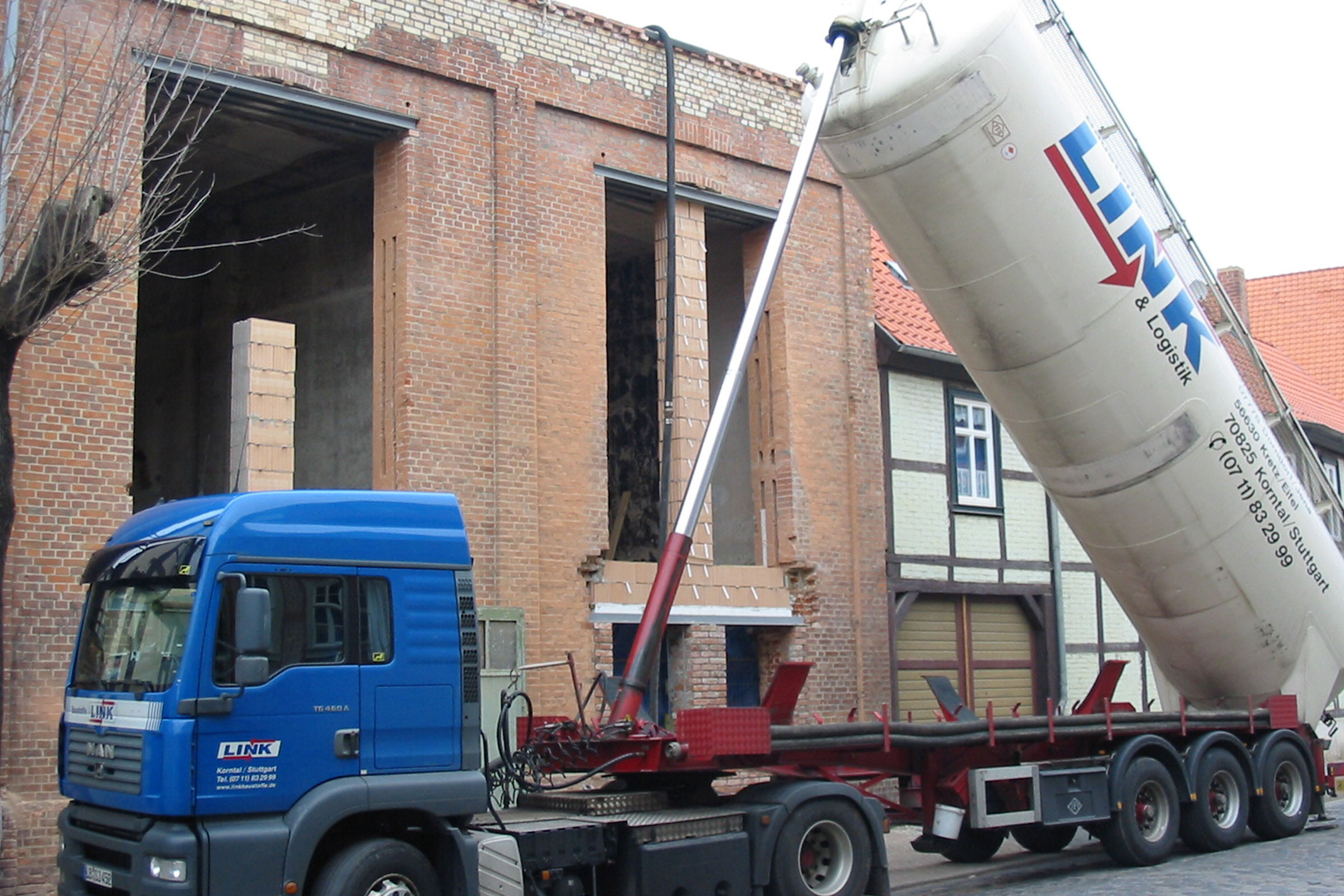 Camion bleu avec silo devant un bâtiment