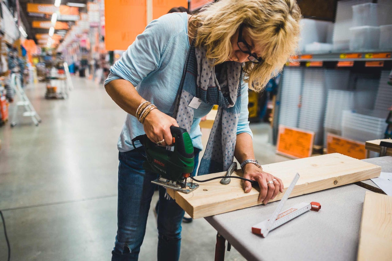 Eine Frau sägt mit einer Stichsäge ein Holzbrett im Hornbach Baumarkt.