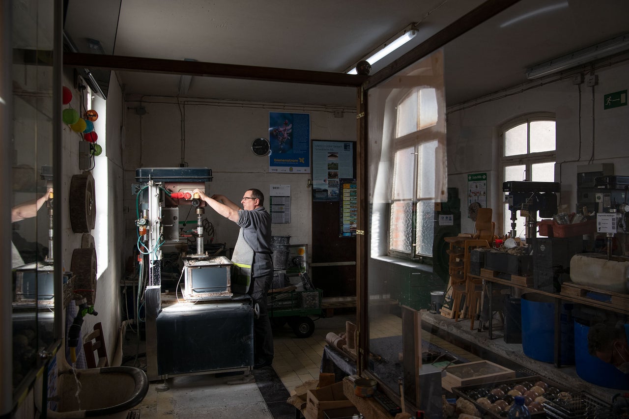 Werkstatt mit Werkzeugmaschinen und einer Person, die an einer Maschine arbeitet.
