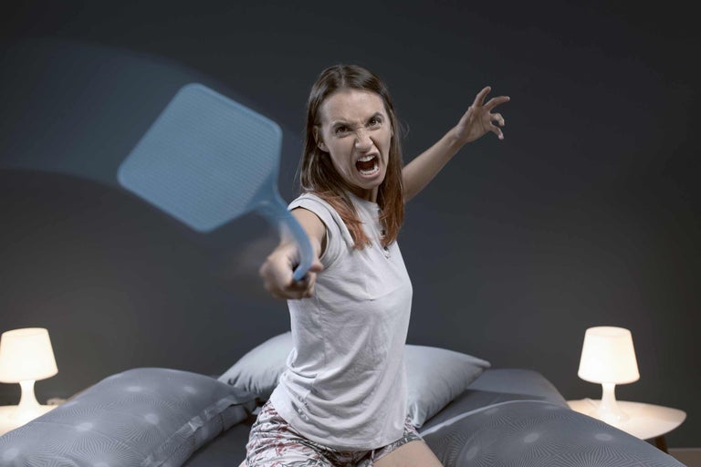 Frau mit Fliegenklatsche im Schlafzimmer